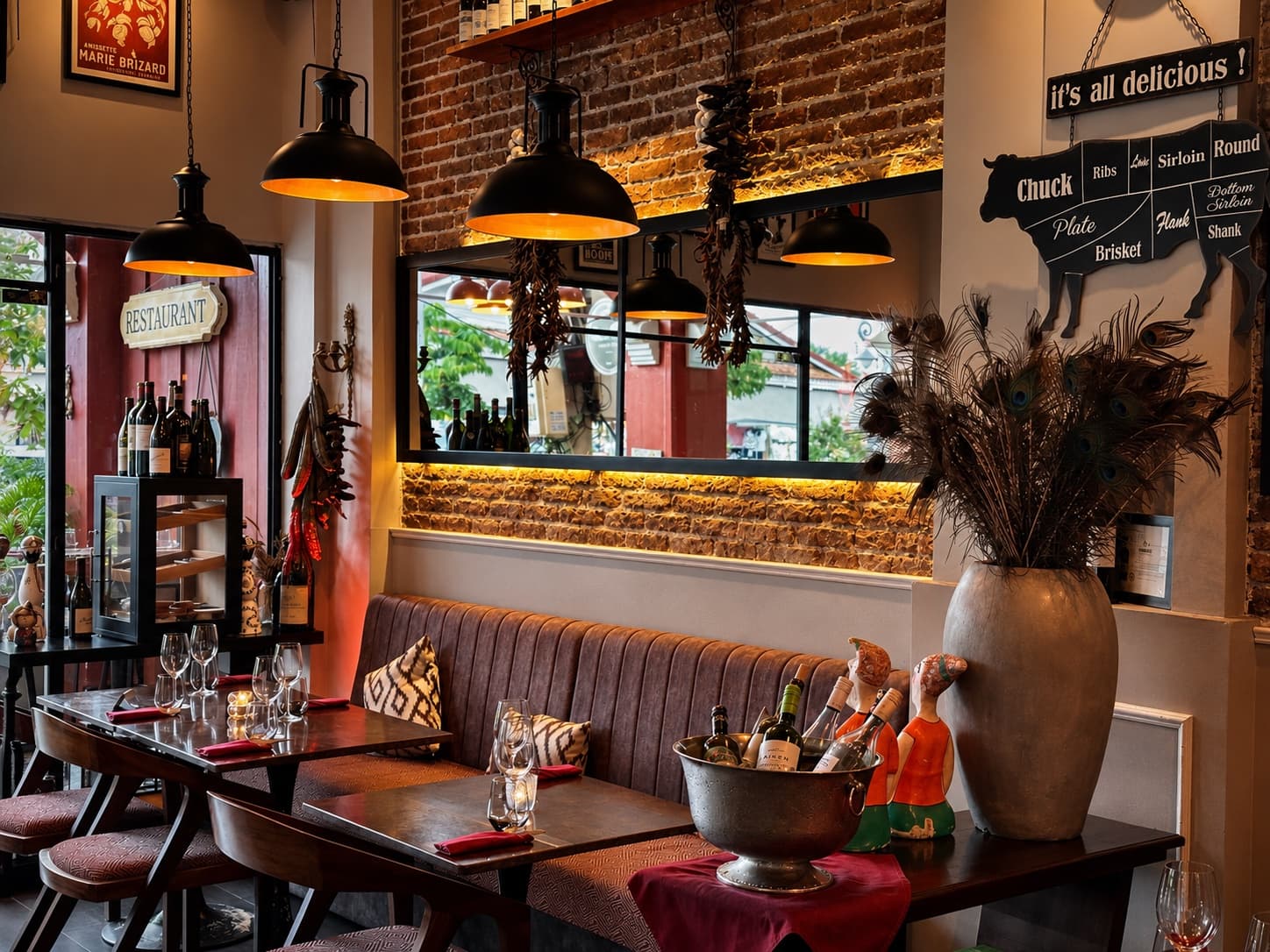 Somaha's warmly lit dining room, with set tables, exposed brick walls, pendant lights, and a display of wine